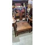 A 19TH CENTURY OAK LOW ELBOW CHAIR WITH VASE-SHAPED SPLAT AND SOLID PLANK SEAT, 92CM HIGH