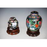 CHINESE PORCELAIN BLACK GROUND FAMILLE ROSE JAR AND COVER ON WOOD STAND, TOGETHER WITH ANOTHER