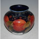 SMALL MOORCROFT POTTERY VASE DECORATED WITH POMEGRANATES ON A BLUE GROUND, 9CM HIGH.
