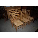 A SET OF SIX OAK RUSH SEATED LADDER BACK DINING CHAIRS COMPRISING TWO CARVERS AND FOUR SIDE CHAIRS