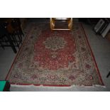 A MACHINE MADE PERSIAN STYLE BURNT ORANGE GROUND CARPET WITHIN BROAD BORDER OF FLORAL PALMET