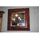 A CARVED OAK SQUARE BEVELLED WALL MIRROR