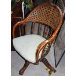 *AN EARLY 20TH CENTURY STAINED BEECH REVOLVING CAPTAINS CHAIR WITH CANEWORK PANEL AND SPINDLE BACK
