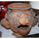*A TERRACOTTA CIRCULAR SHAPED PLANTER WITH TRIPLE MASK DETAIL AND THREE BOW FRONTED OPENINGS ON THE