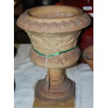 *A FIRECLAY CAMPANA SHAPED URN WITH EGG AND DART BORDER, RELIEF DECORATION OF FLOWERS ON STEPPED