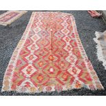A KILIM STYLE FLATWEAVE CARPET, IN TONES OF RED, ORANGE, DARK BROWN, TURQUOISE AND IVORY, 360CM LONG