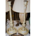 *A PAIR OF CREAM PAINTED CANDLESTICKS WITH TAPERED SPIRAL COLUMNS ON CIRCULAR PLINTH BASES