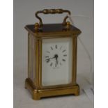 A MINIATURE BRASS CASED CARRIAGE CLOCK WITH BLACK AND WHITE ROMAN NUMERAL DIAL, THE BACK PLATE