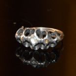 A FIVE STONE RING, WITH FIVE ROSE CUT DIAMONDS IN A WIDE WHITE METAL MOUNT ON A YELLOW METAL BAND,