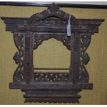 A LATE 19TH / EARLY 20TH CENTURY INDIAN CARVED TEAK WALL MOUNTED FRAME, OF ARCHITECTURAL WINDOW FORM