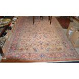 A MACHINE MADE PERSIAN STYLE CARPET, THE RECTANGULAR PEACH COLOURED GROUND DECORATED WITH STYLISED