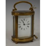 A LATE 19TH / EARLY 20TH CENTURY OVAL SHAPED BRASS CARRIAGE CLOCK WITH BLACK AND WHITE ROMAN NUMERAL