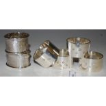 A COLLECTION OF NAPKIN RINGS TO INCLUDE A SET OF FOUR SHEFFIELD SILVER NAPKIN RINGS OF PLAIN