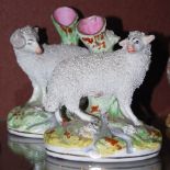 A PAIR OF 19TH CENTURY STAFFORDSHIRE POTTERY SPILL VASES, ONE WITH RAM, THE OTHER WITH SHEEP WITH