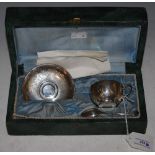 A CASED WHITE METAL TEA CUP, SAUCER AND SPOON