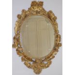 A 19th century gilt wood wall mirror, the flower and foliate scroll carved frame enclosing an oval
