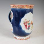 A Chinese porcelain tankard, Qing Dynasty, decorated with a shaped oval panel enclosing figures on a