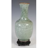 A Chinese porcelain crackle glazed celadon vase, Qing Dynasty, with pierced and carved wood stand,