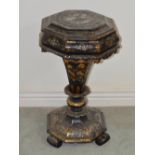 A Victorian papier maché work table, the hinged octagonal top opening to a fitted interior on a