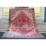 A large early 20th century Persian Heriz carpet, the deep red field with various angular rosettes,