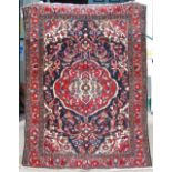 An early 20th century Persian carpet, the indigo field with a large central red medallion with