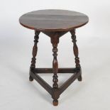 An 18th century oak cricket table, the patinated plank top on three tapering legs united by