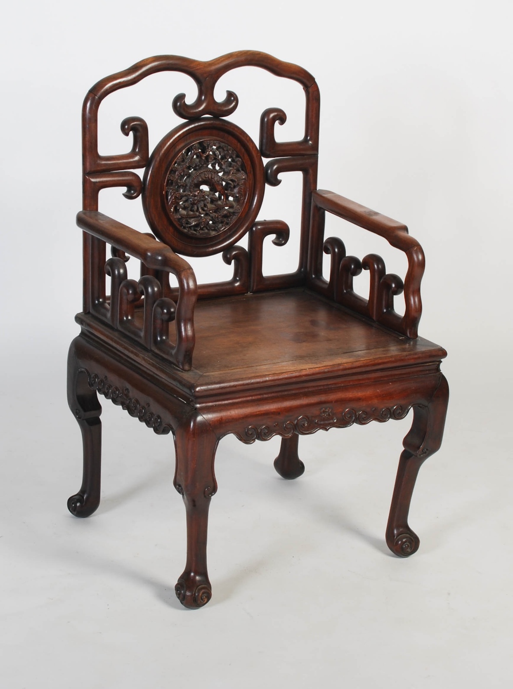 A Chinese carved darkwood armchair, late 19th/ early 20th century, the shaped back rail enclosing