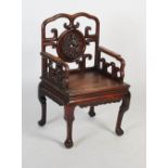 A Chinese carved darkwood armchair, late 19th/ early 20th century, the shaped back rail enclosing