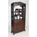 A Chinese carved darkwood display cabinet, Qing Dynasty, the arched top with a carved pediment