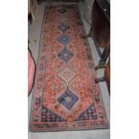 A 20TH CENTURY PERSIAN RUNNER, THE RECTANGULAR MADDER GROUND CENTRED WITH SEVEN LOZENGE SHAPED