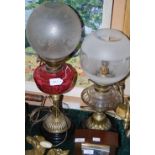 TWO BRASS PARAFFIN BURNING OIL LAMPS CONVERTED TO ELECTRICITY, ONE WITH CRANBERRY GLASS RESERVOIR,