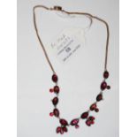 A YELLOW METAL AND FOIL BACKED GARNET NECKLACE