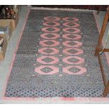 PERSIAN RUG, 20TH CENTURY. THE PINK GROUND DECORATED WITH TWO ROWS OF EIGHT LOZENGE-SHAPED