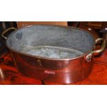 A TWIN HANDLED COPPER AND BRASS OVAL SHAPED SAUCE PAN