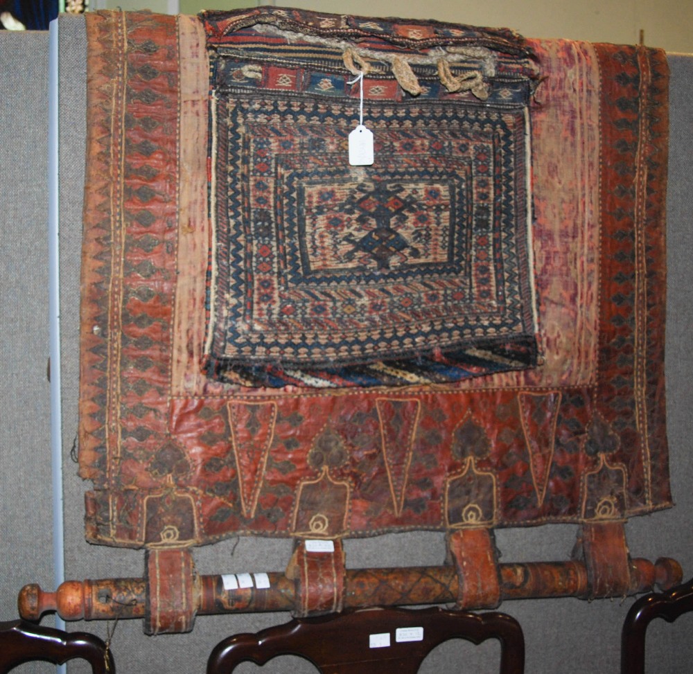 AN EASTERN EMBROIDERED LEATHER AND FABRIC WALL HANGING, TOGETHER WITH A SADDLEBAG