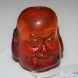 AN AMBER COLOURED BEAD CARVED IN THE FORM OF A BUDDHAS HEAD