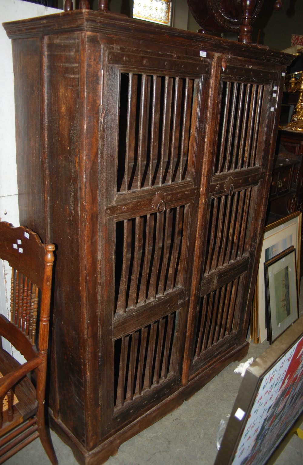 A STAINED WOOD FOOD HUTCH WITH TWO CUPBOARD DOORS, EACH WITH METAL SPINDLE DETAILS, OPENING TO
