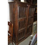 A STAINED WOOD FOOD HUTCH WITH TWO CUPBOARD DOORS, EACH WITH METAL SPINDLE DETAILS, OPENING TO