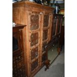 AN EASTERN STYLE CARVED WOOD AND METAL TWO DOOR CUPBOARD, THE DOORS WITH BOSS DETAIL OPENING TO A