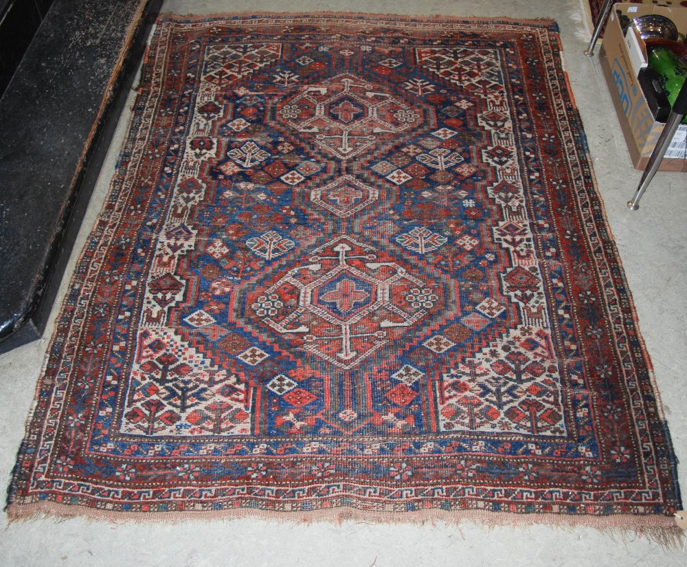 A PERSIAN RUG, THE RECTANGULAR FIELD DECORATED WITH TWO LOZENGE SHAPED MEDALLIONS WITHIN A MADDER