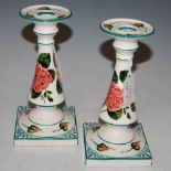 A PAIR OF GRISELDA HILL POTTERY CANDLESTICKS DECORATED WITH ROSES AND FOLIAGE