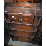 AN EARLY 20TH STAINED OAK SIDE CABINET FITTED WITH TWO CUPBOARD DOORS OVER THREE OPEN SHELVES WITH