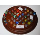 A MAHOGANY SOLITAIRE BOARD AND ASSORTED MARBLES