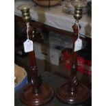 A PAIR OF MAHOGANY AND BRASS MOUNTED CANDLESTICKS WITH TURNED STEMS AND CIRCULAR BASES