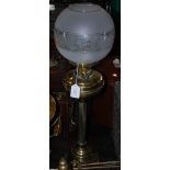 A BRASS OIL BURNING LAMP WITH CLEAR AND FROSTED GLASS SHADE