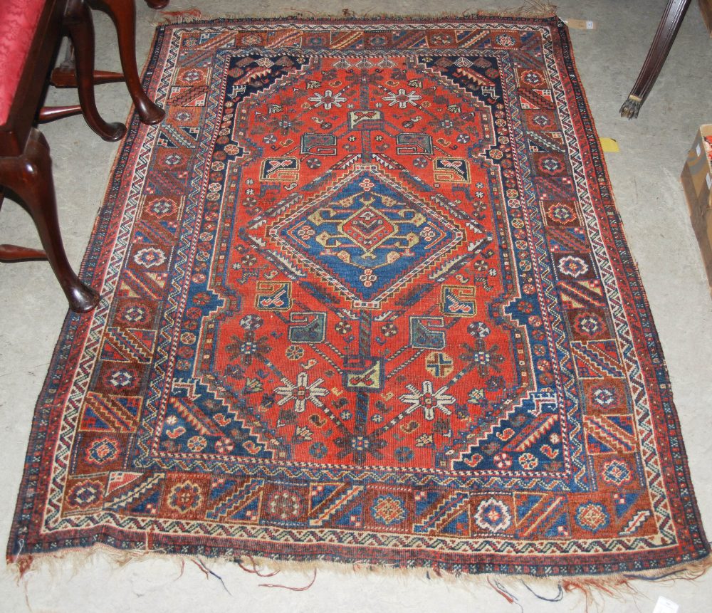 A PERSIAN RUG, THE RECTANGULAR MADDER GROUND CENTRED WITH A LARGE BLUE GROUND MEDALLION WITHIN A