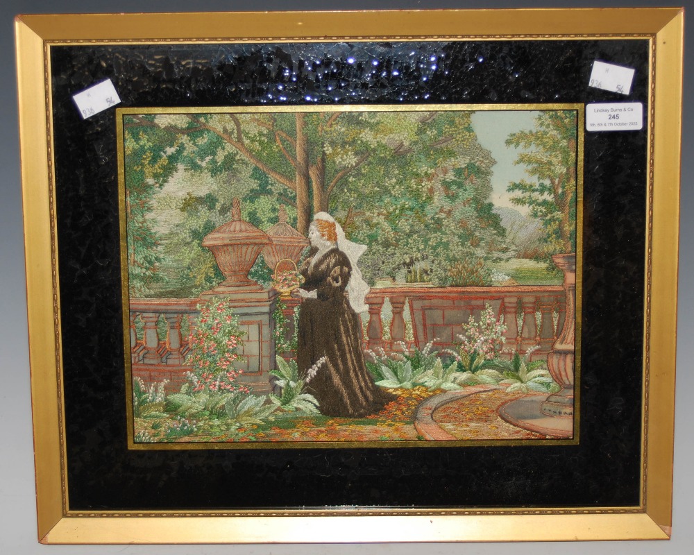 LATE 19TH/ EARLY 20TH CENTURY NEEDLEWORK PICTURE DEPICTING LADY IN A GARDEN WITHIN VERRE EGLOMISE