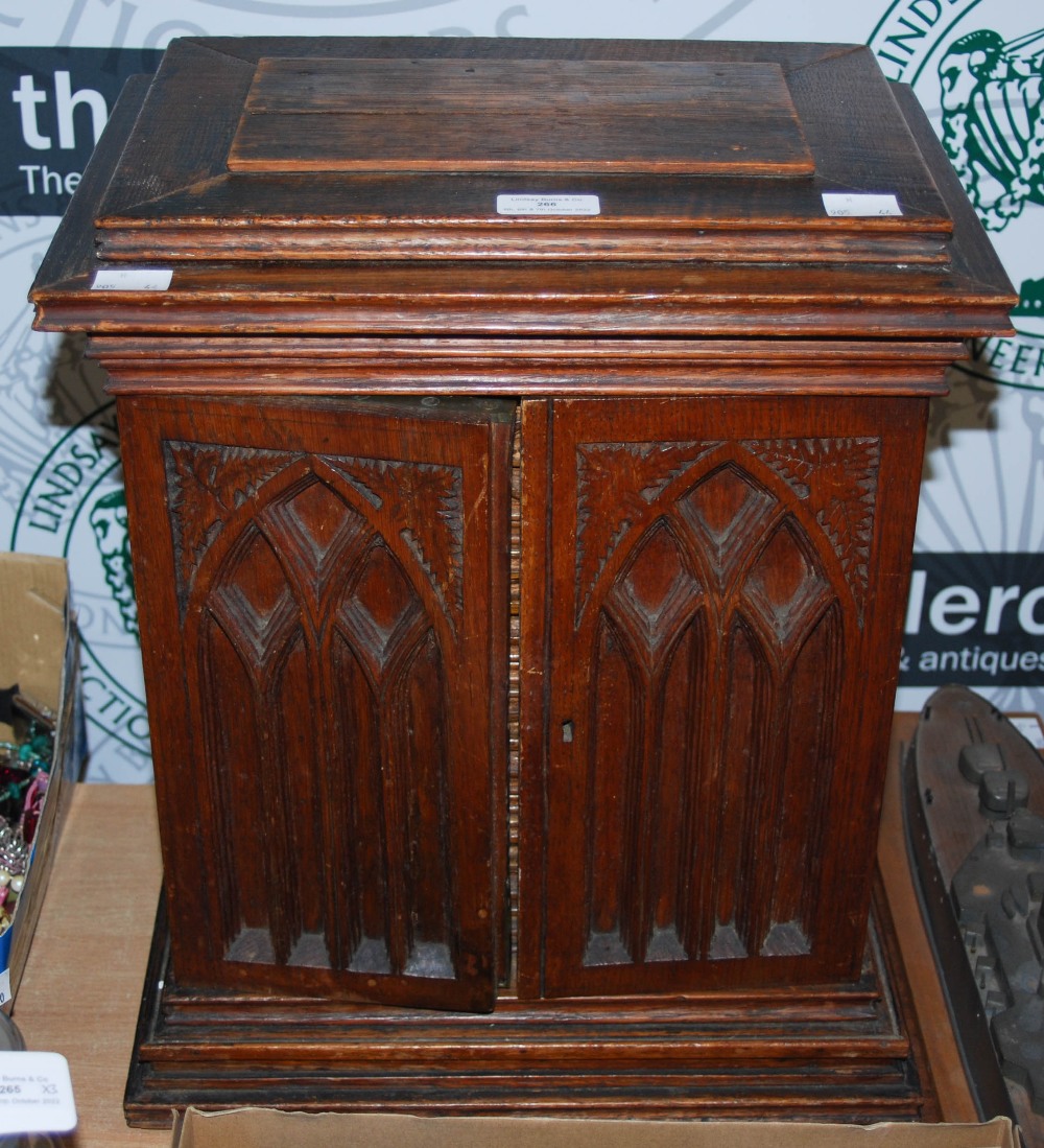 A CARVED OAK TABLE TOP CABINET IN THE GOTHIC TASTE, TWO CUPBOARD DOORS OPENING TO FOUR DRAWERS