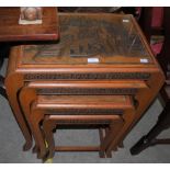 A NEST OF FOUR TABLES WITH CARVED CHINESE DETAILS AND REMOVABLE GLASS TOPS