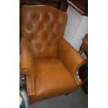 A BROWN LEATHERETTE BUTTON-BACK ARMCHAIR